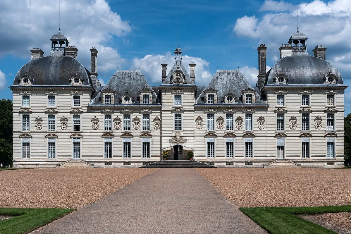 The symmetrical white stone front of the Château de Cheverny, with a domed pavilion at each end and a gravel drive leading to the central entrance
